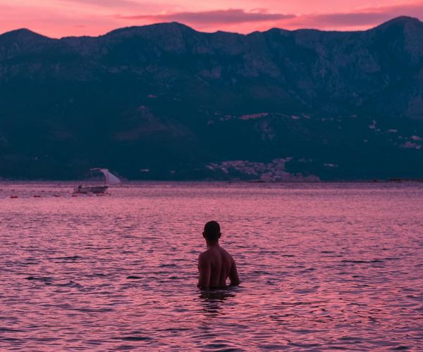 A person meditating peacefully by a lake at sunrise.